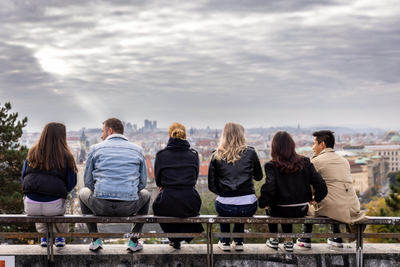 UNYP MBA students sitting on a viewpoint ledge and looking out over the Prague skyline.
